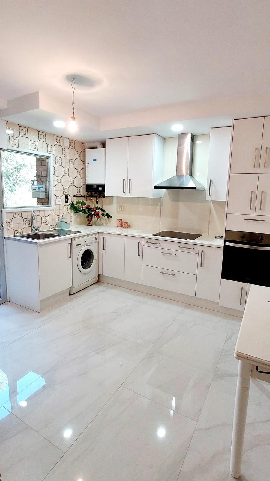 Cocina blanca reformada con suelo porcelánico