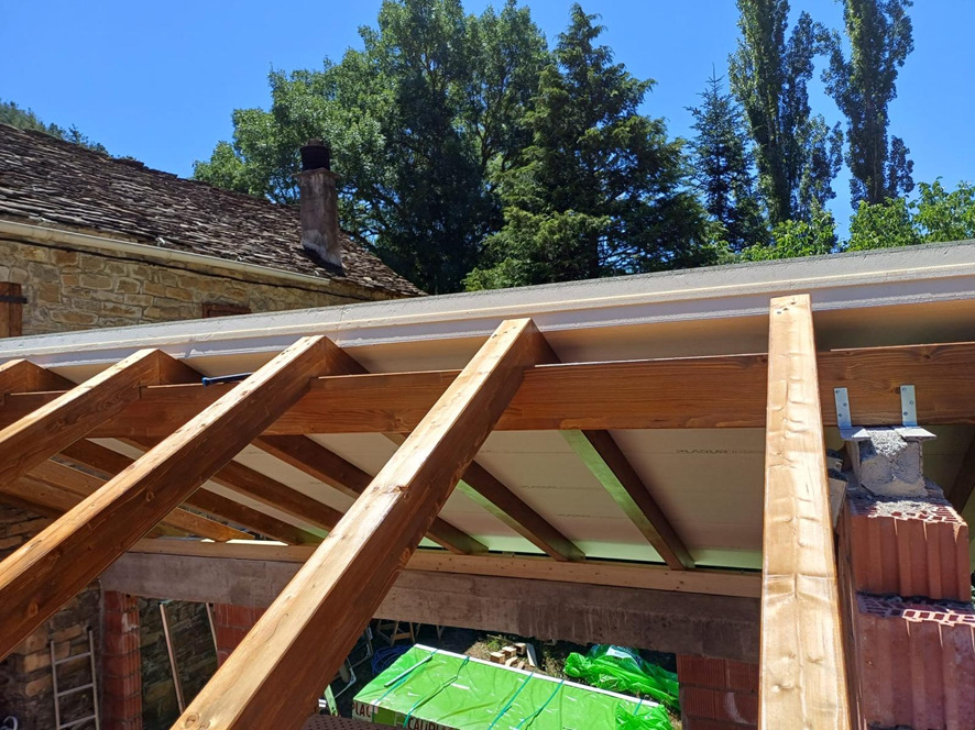 Estructura de madera de un porche sobre una casa de piedra