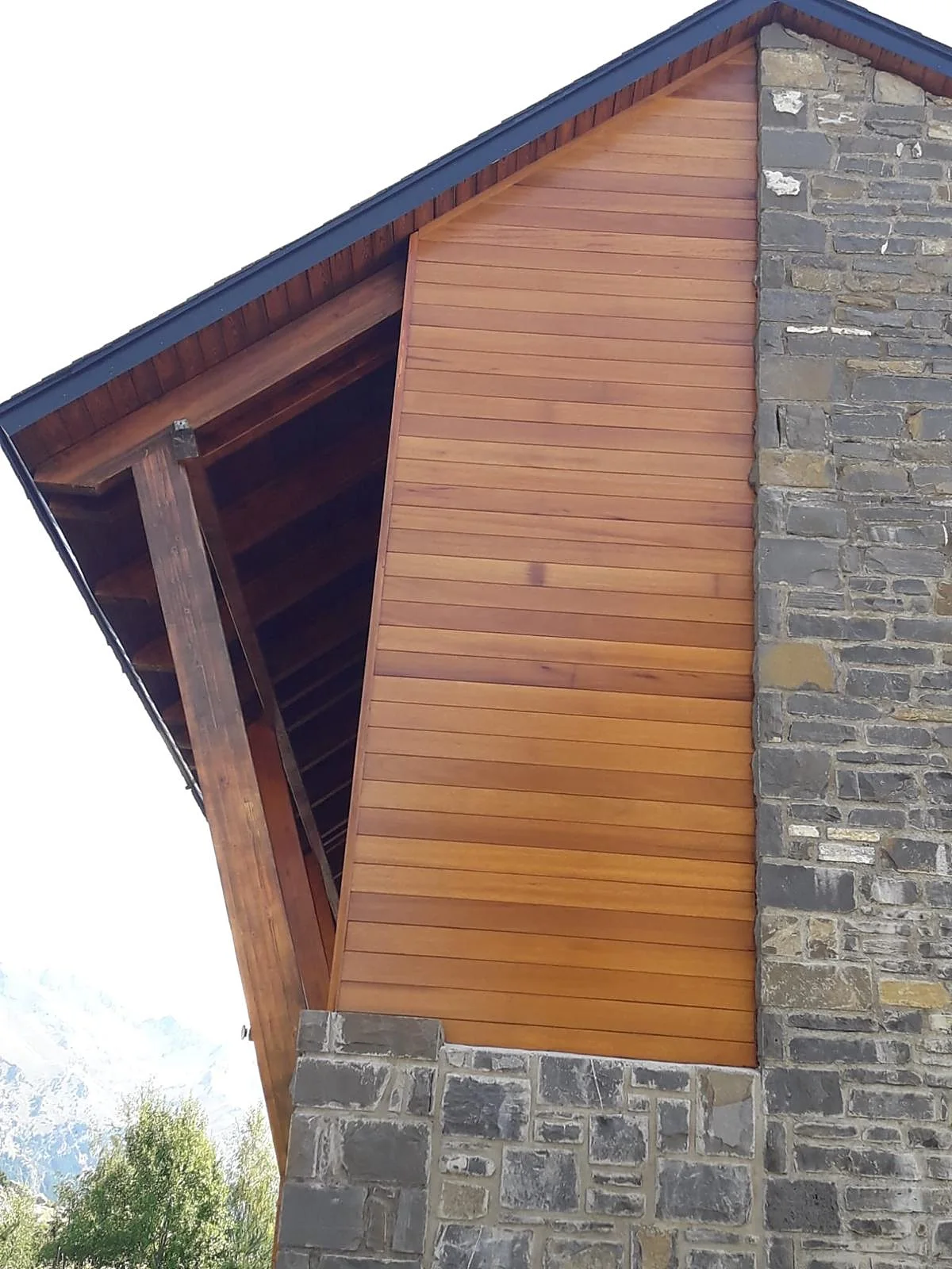 La misma fachada con el revestimiento de madera nuevo terminado